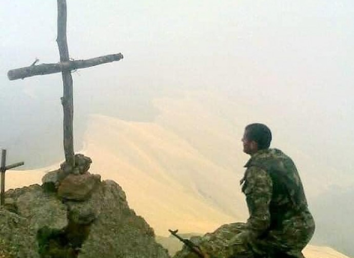 Soldado reza na frente da cruz